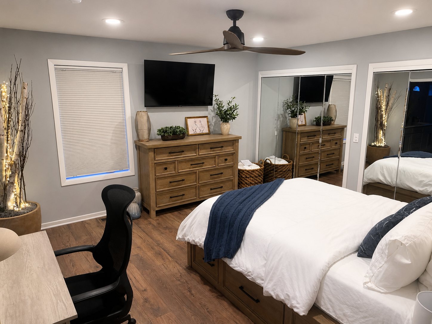 Wide view of the one-bedroom bedroom with dresser, TV, and mirrored closets